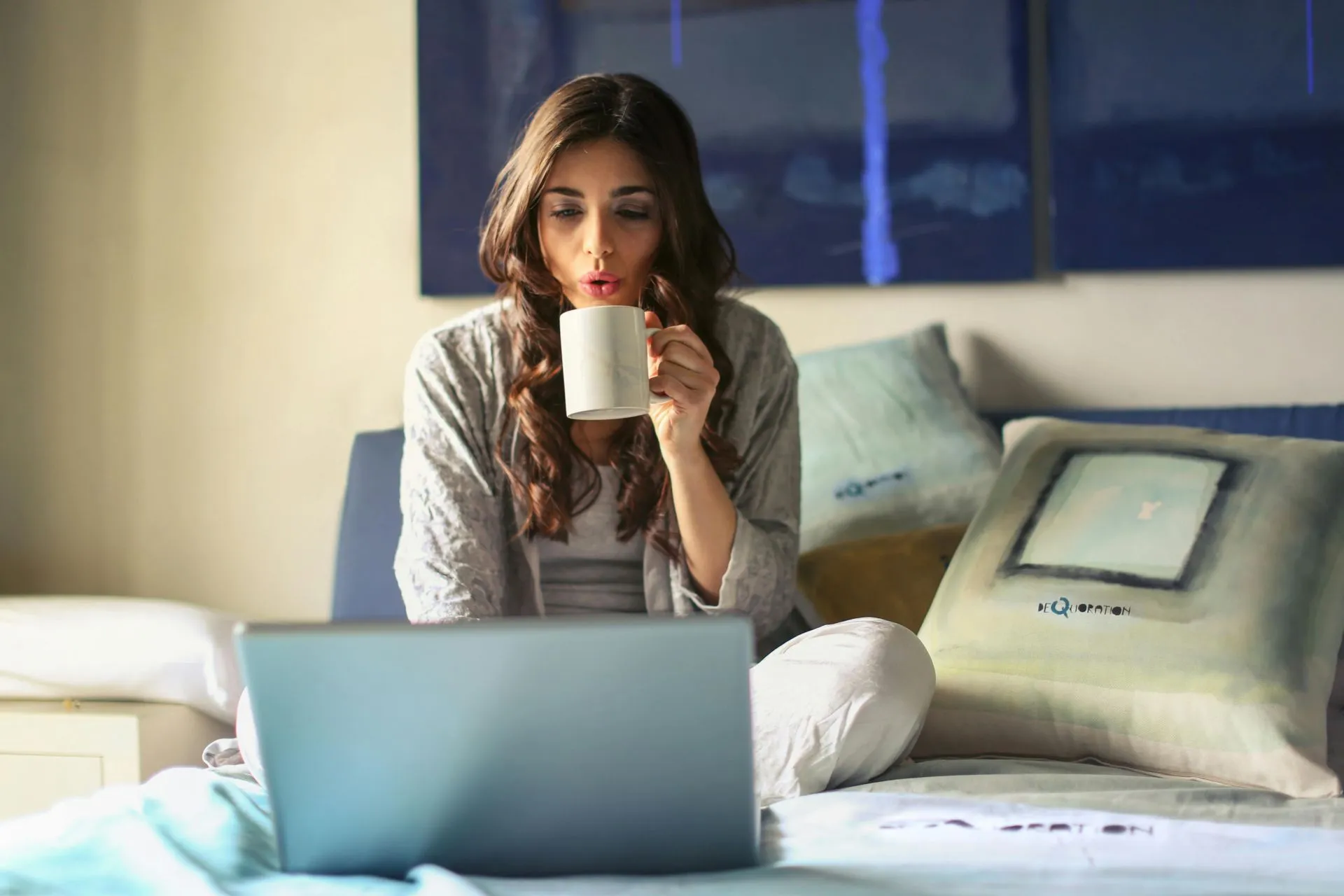 A woman working on a laptop from her sofa